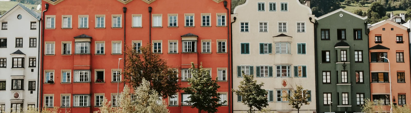 Farbenfrohe Wohnhäuser in Innsbruck vor den Tiroler Bergen